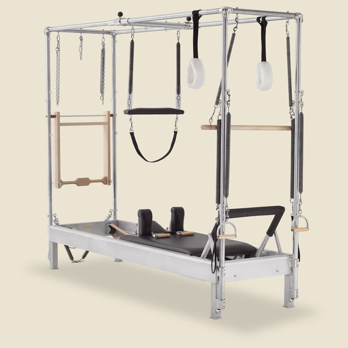 Gratz Pilates Cadillac conversion reformer with leg springs, straps, and fur-lined handles attached.