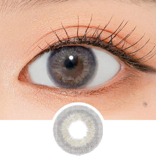 Close-up shot of a model's eye wearing Lensrang Romantic Grey color contacts with prescription, paired with K-beauty-inspired eye makeup, showing the brightening and enlarging effect of the circle contact lens on dark brown eyes, above a cutout of the contact lens pattern with limbal ring on a white background.