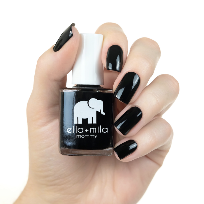 Lights Out pure black nail polish manicure on a light skin tone with the bottle