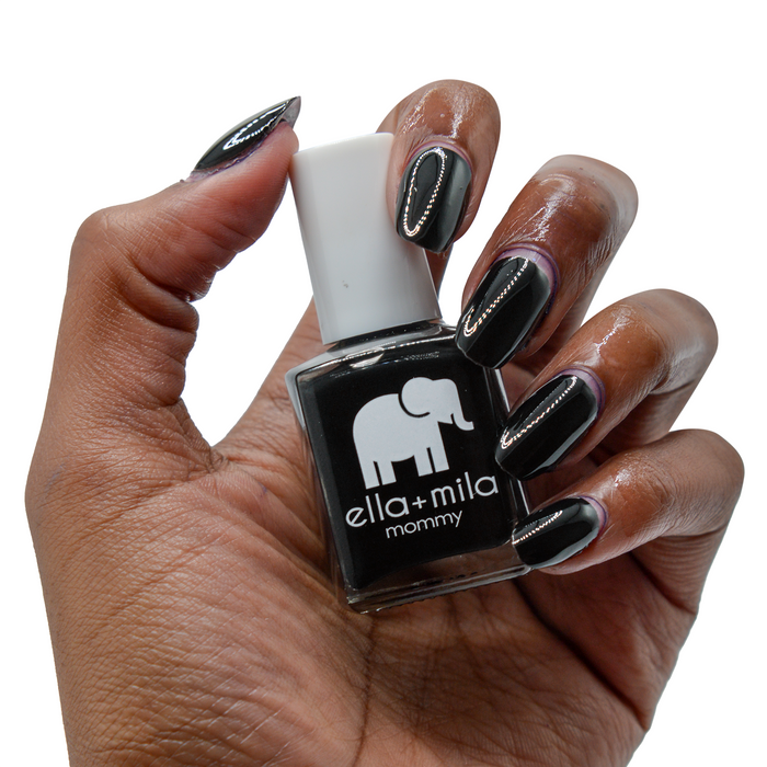 Lights Out black nail polish on a deep skin tone, hand holding the bottle