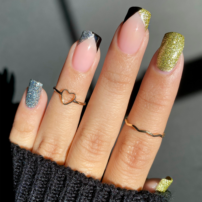 Lights Out black French tip manicure with gold glitter accents and rings