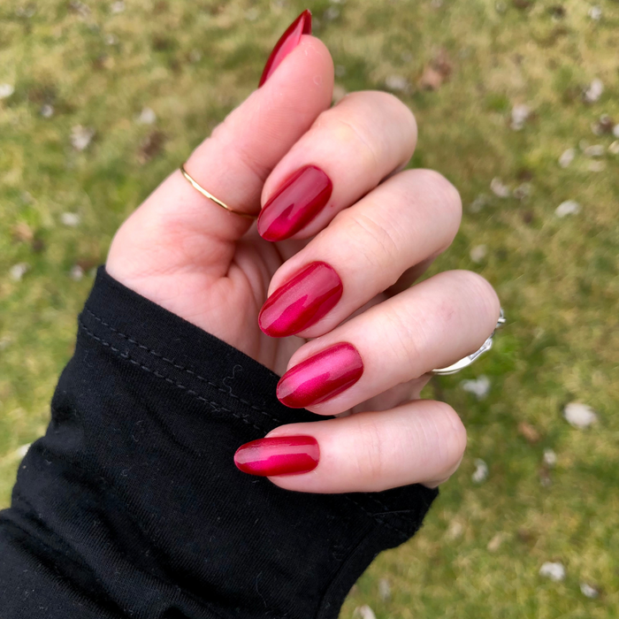 Magenta Velvet - Press-On | Medium | Oval showing hand with shiny medium oval magenta press-on nails outdoors on grass background