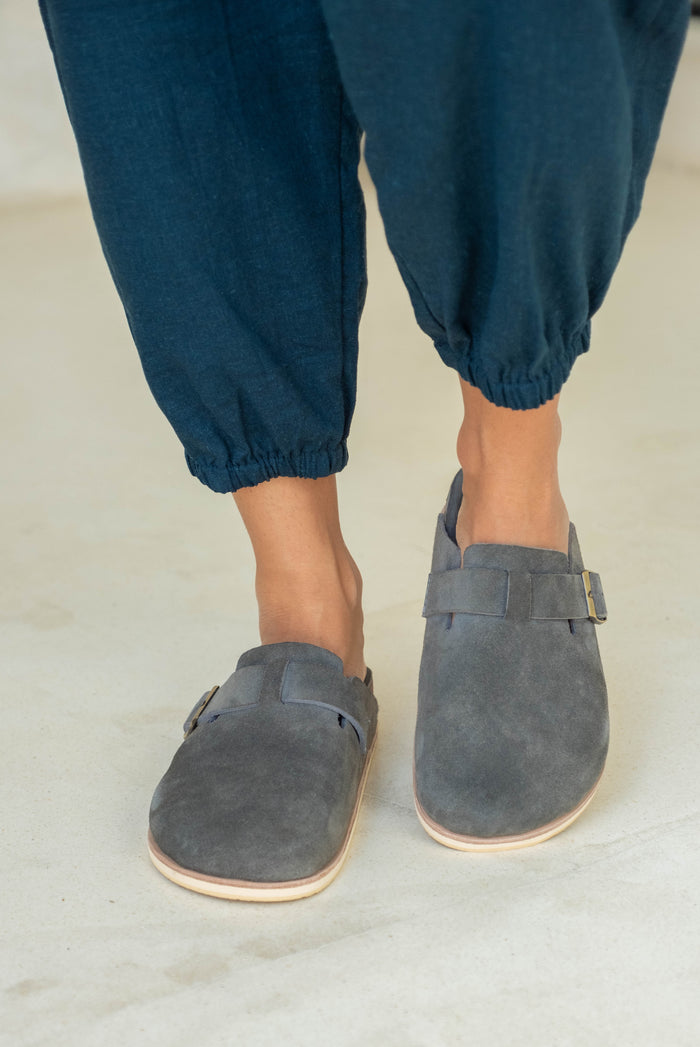 Close-up of blue slip-on shoes paired with dark blue loose pants.