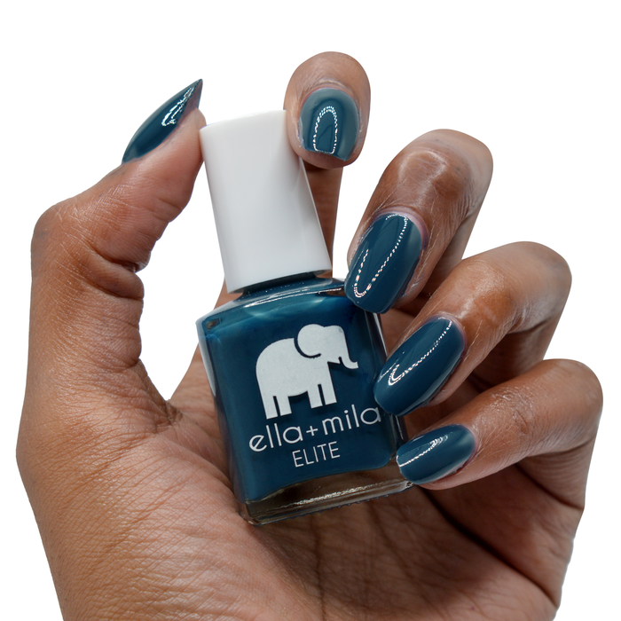Mediterranean Mist dark teal nail polish on a deep skin tone, hand holding the bottle