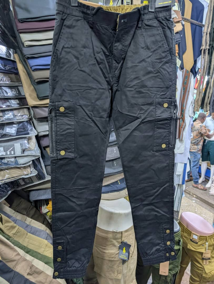Men's black cargo pants with zippered pockets and brass snap buttons