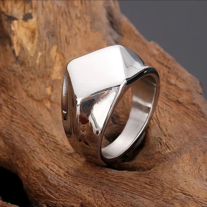 Men’s polished gold square face ring featuring a bold silhouette on a wooden background.