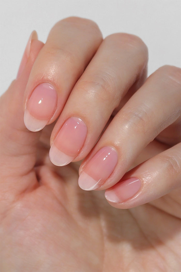 Close-up of nails painted with Cirque Colors Hint Tint: Blush nail polish, showcasing a glossy, clear bright pink tint that enhances the natural nail with a subtle wash of color. The ultra-transparent finish achieves a polished 'my nails but better' look