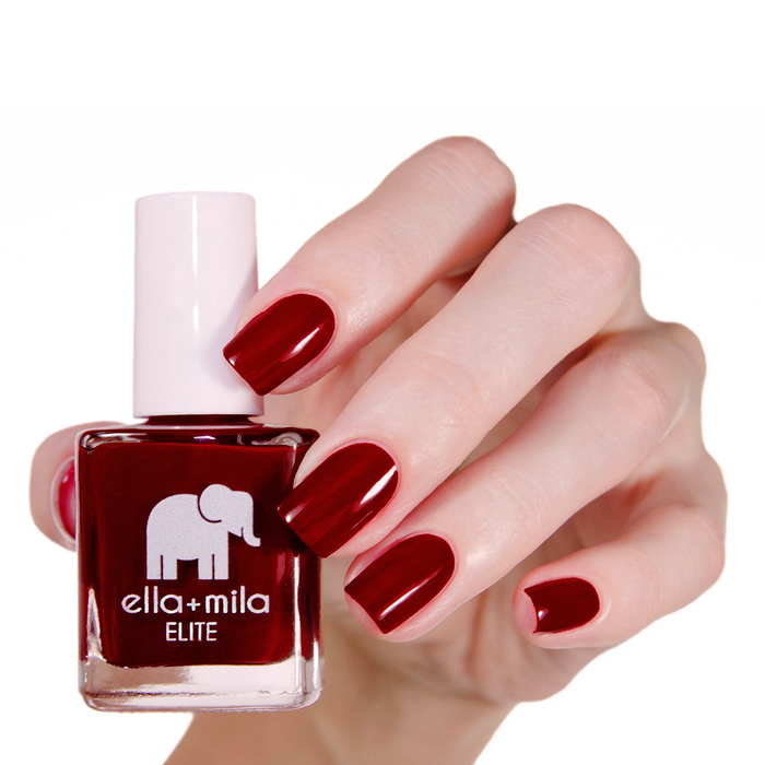 Naughty Not Nice ruby red nail polish manicure on a light skin tone with the bottle