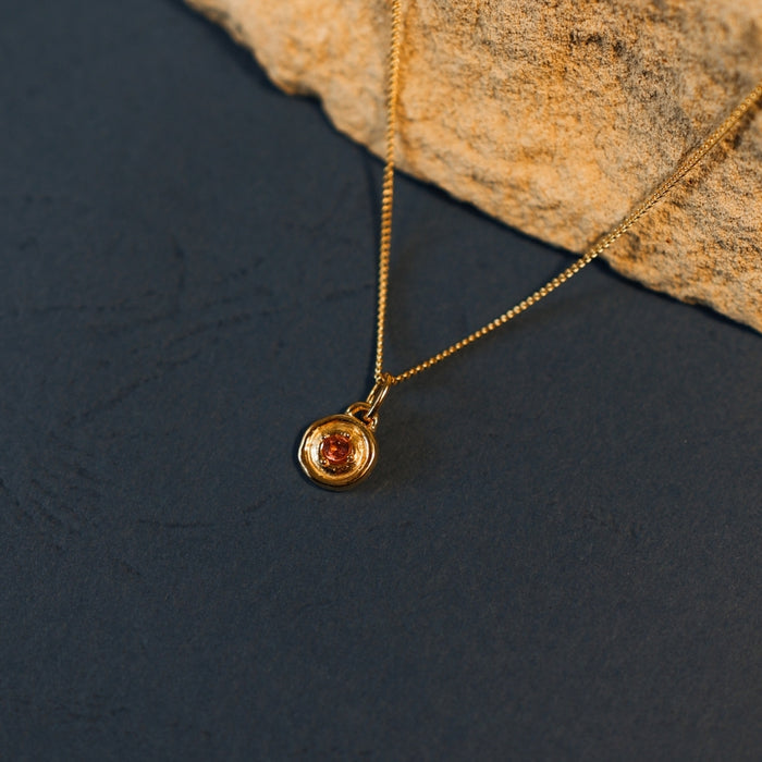 Gold necklace with a pendant on a dark surface