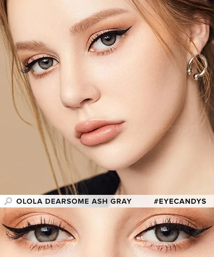 A close-up of a woman wearing Olola Dearsome Ash Grey contact lenses by Olola for dark eyes, with winged eyeliner, nude lipstick, and hoop earrings. Bottom shows a detailed view of her eyes. Text: "Olola Dearsome Ash Grey #Eyecandys.