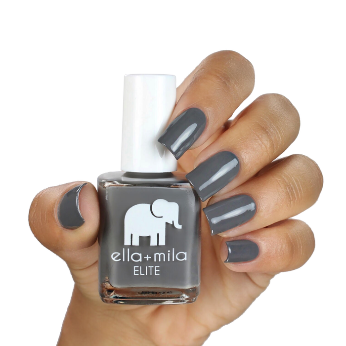 On the Runway dark grey nail polish on a medium skin tone, hand holding the bottle