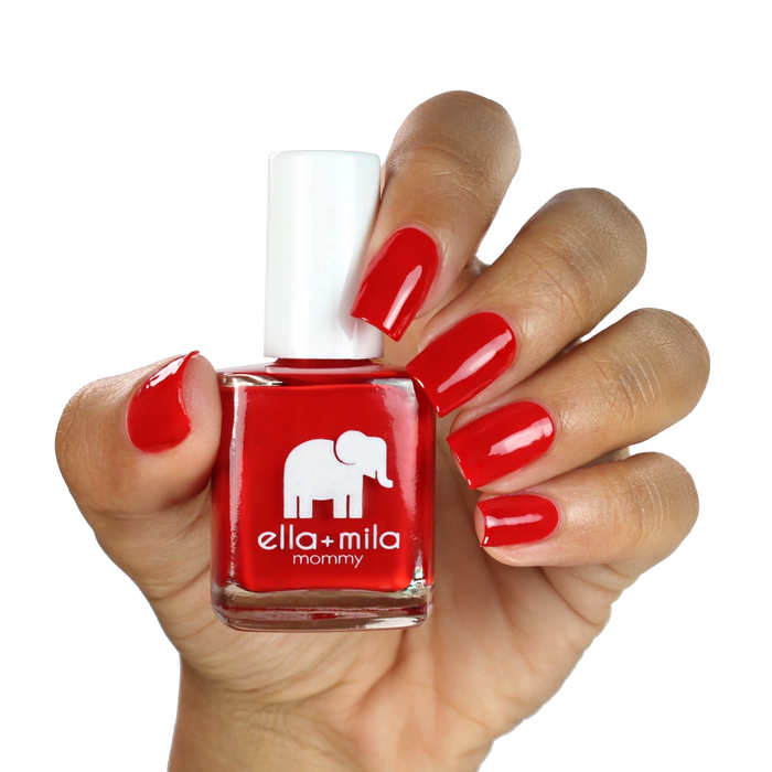 Paint the Town Red red nail polish on a medium skin tone, hand holding the bottle