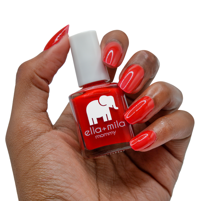 Paint the Town Red red nail polish on a deep skin tone, hand holding the bottle
