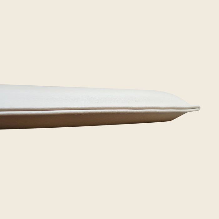 Cream upholstered Pilates headrest pillow shown from a slim side profile.