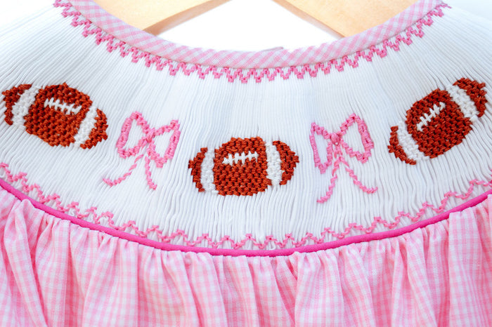 Smocked Pink Football Bubble in pink gingham with a hand-smocked neckline of footballs and bows and easy snap closure