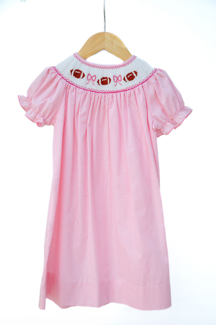 Smocked Pink Football Dress in pink gingham with a hand-smocked neckline of footballs and bows