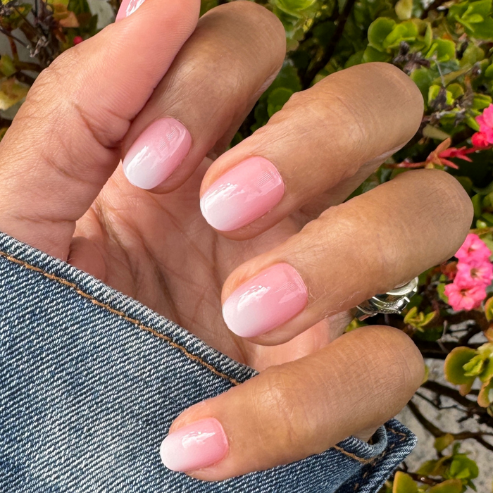 Pink Syrup Gradient - Press-On | Extra Short | Round showing hand with extra short round dusty pink to milky white gradient press-on manicure outdoors
