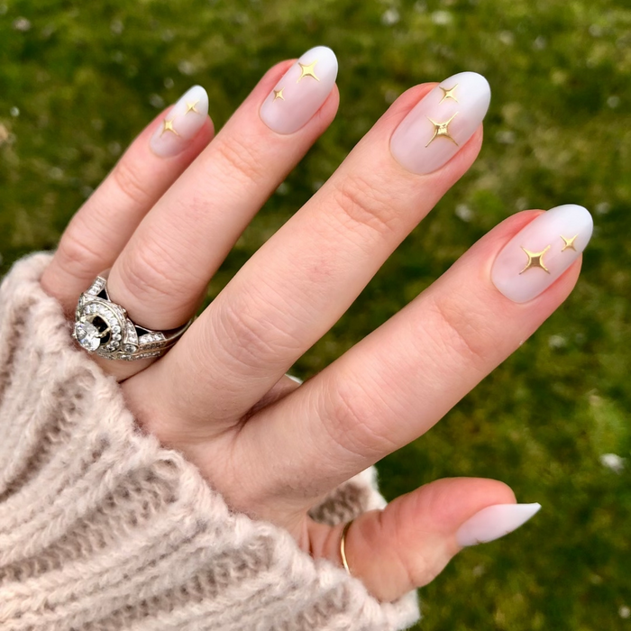 Puffy Sparkle - Press-On | Medium | Oval showing hand with medium oval press-on nails in neutral white and raised gold star accents