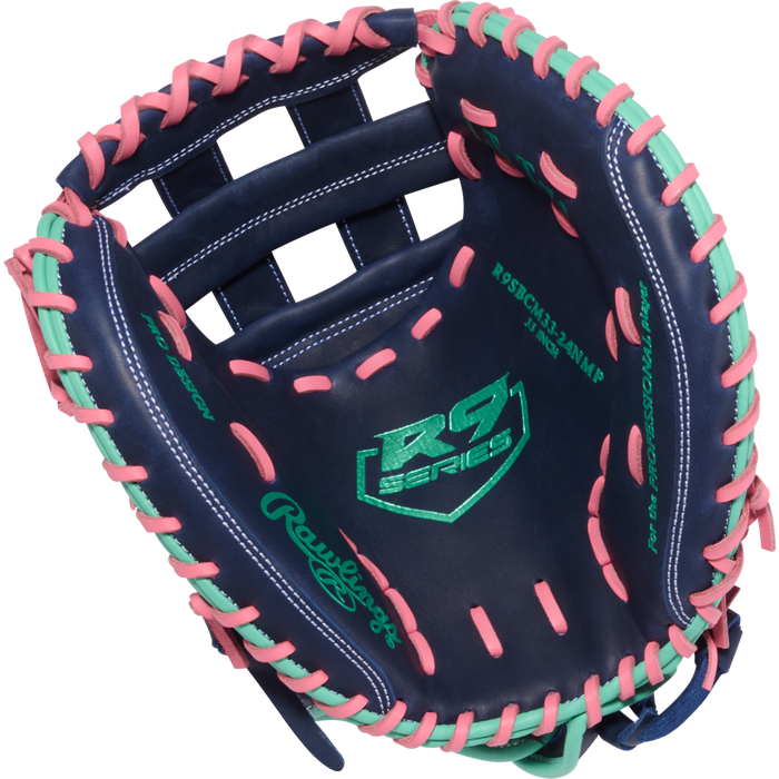 The Rawlings R9 33" Fastpitch Catcher's Mitt (R9SBCM33-24NMP) features navy blue leather with pink and mint lacing, RS Series and green Rawlings logos—an eye-catching softball glove built for elite catchers.