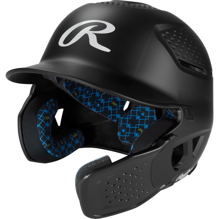 The Rawlings RX2 Reverse Matte Batting Helmet: RX2REVMAT in black features a reversible flap system, protective face guard, blue geometric patterned padding, NOCSAE-certified protection, and a matte finish.
