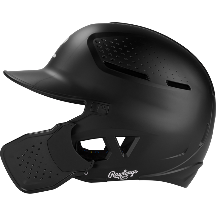 A black Rawlings RX2 Reverse Matte Batting Helmet: RX2REVMAT, featuring a protective face guard, ventilation holes, and reversible flap system, is shown in profile against a white background; NOCSAE-certified for safety.