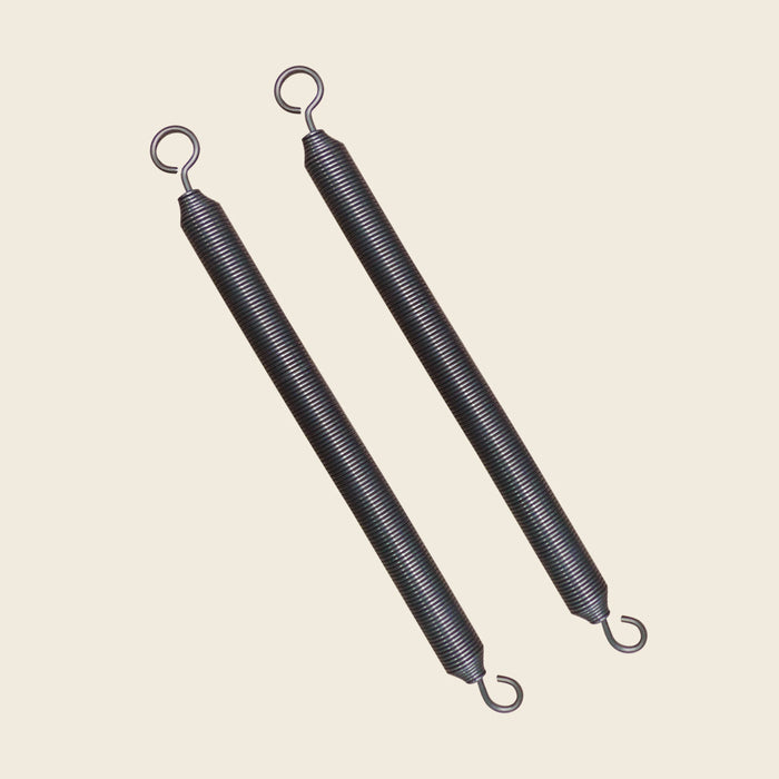 Pair of black coiled Gratz Pilates Reformer springs with looped hook ends on beige.