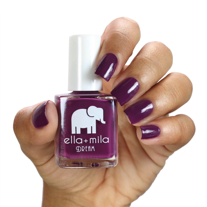 Rising Violet deep violet nail polish on a medium skin tone, hand holding the bottle