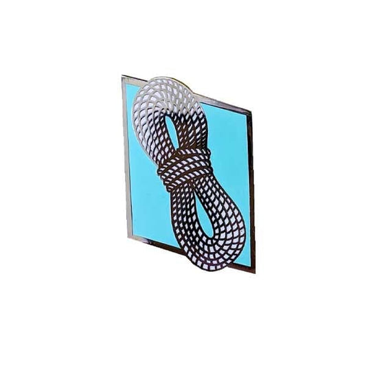 A square enamel pin featuring a black and white patterned rope knot design over a light blue background, set against a plain white studio backdrop.