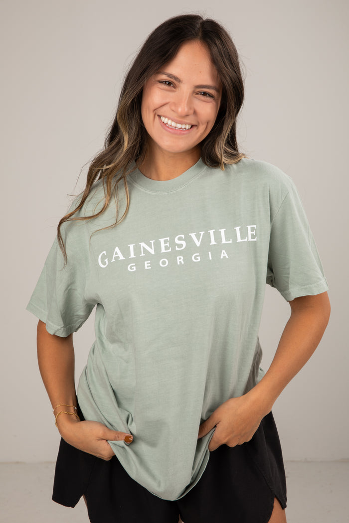 Woman wearing a green t-shirt with 'Gainesville Georgia' text on a plain background