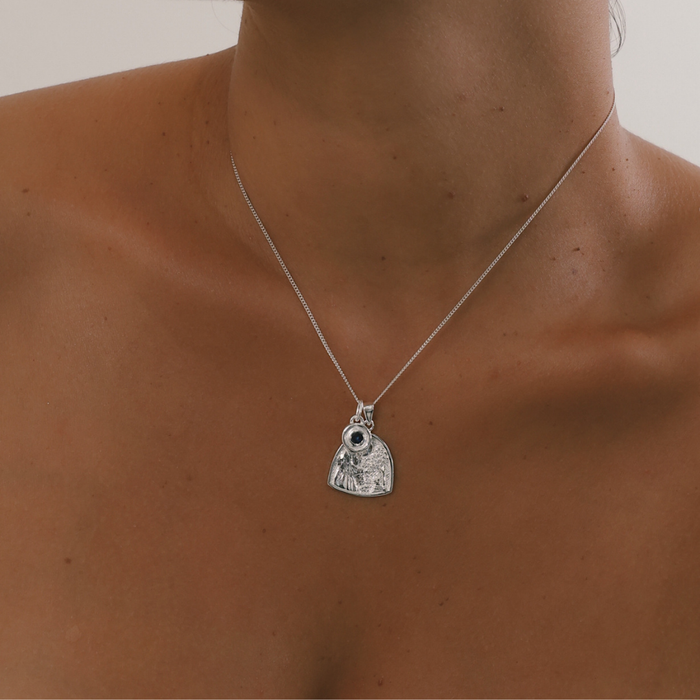 Necklace with a pendant on a person's neck against a neutral background