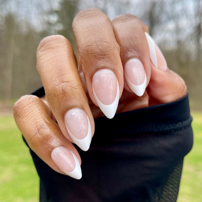 Sharp French - Press-On | Medium | Stiletto showing hand with pointed stiletto nails featuring classic white french tip manicure outdoors