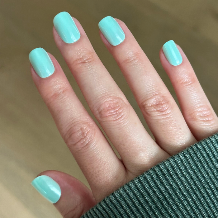 Slam Dunk Chrome - Press-On | Extra Short | Squoval turquoise press-on nails with glossy finish on hand wearing green sleeve indoors