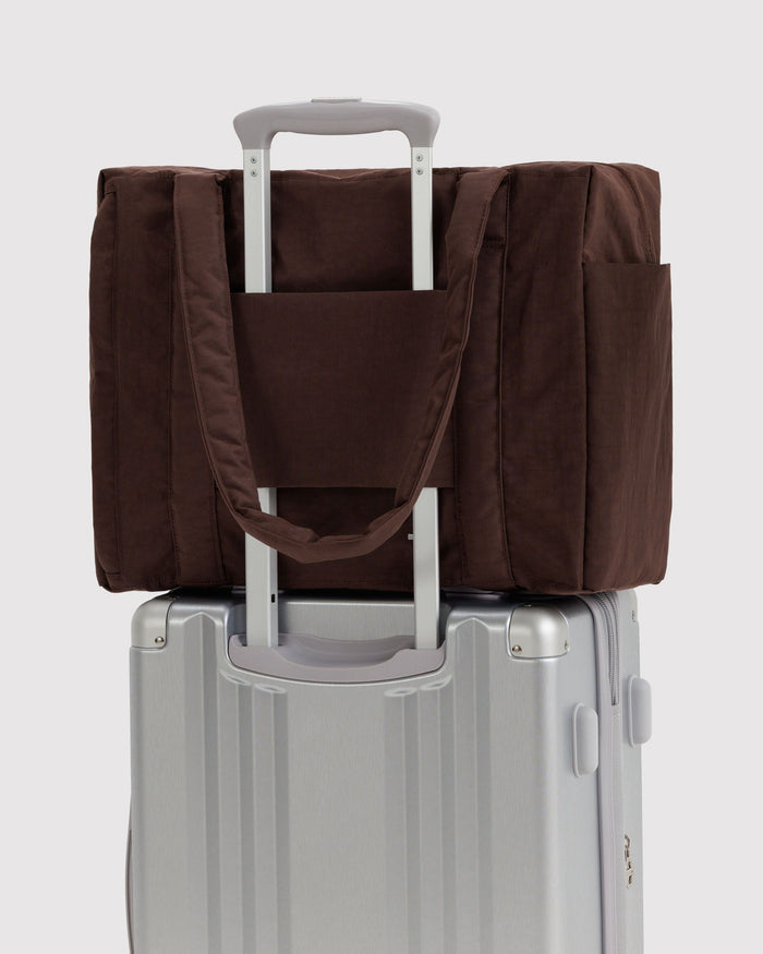 Brown carry-on tote bag attached to a rolling suitcase with a handle pass-through