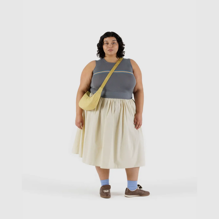 Small crescent nylon crossbody bag in light yellow worn crossbody with strap tag