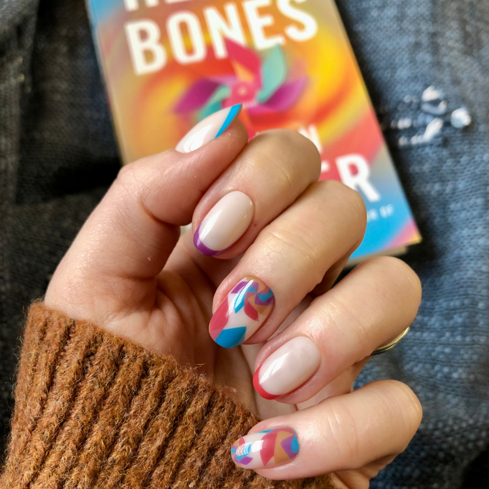 Spinning Pinwheel - Press-On | Short | Round showing short round nails with colorful pinwheel accents on neutral base over book cover