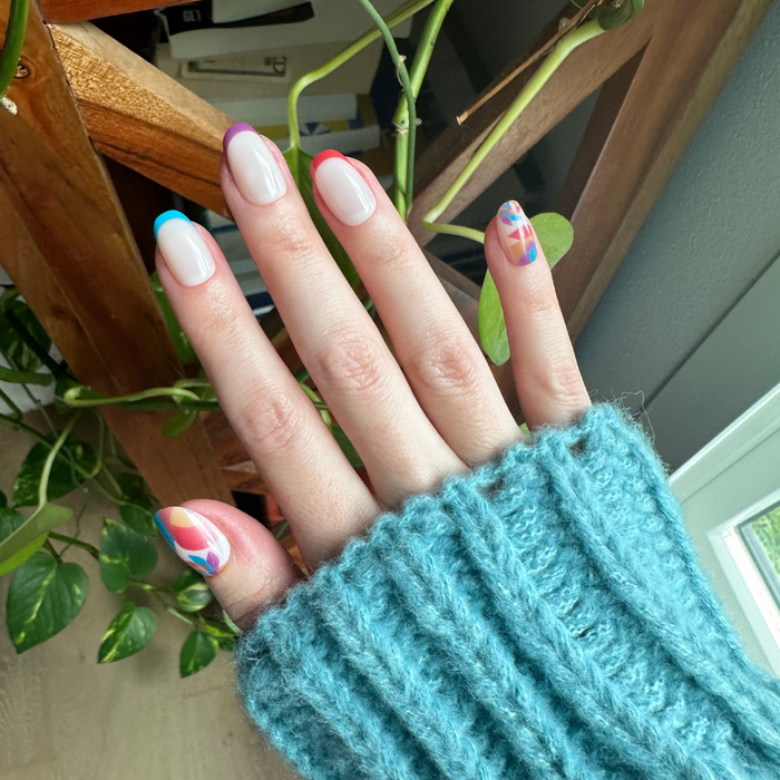 Spinning Pinwheel - Press-On | Short | Round showing short round nails with neutral French tips and colorful pinwheel accents indoors