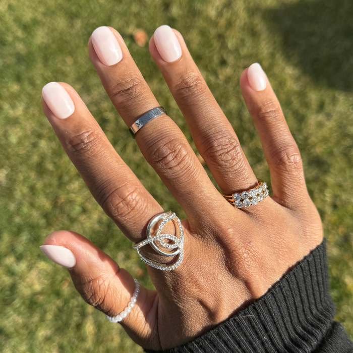 Sugar Glaze - Press-On | Extra Short | Round showing sheer white nails with shiny chrome glaze on hand adorned with silver and gold rings