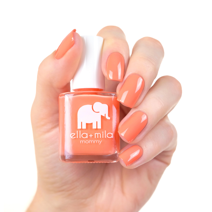 Sunkissed coral orange nail polish manicure on a light skin tone with the bottle