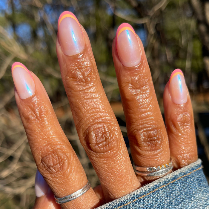 Sunset Double French - Press-On | Medium | Oval showing hand with medium oval iridescent nails and orange magenta double french tips outdoors