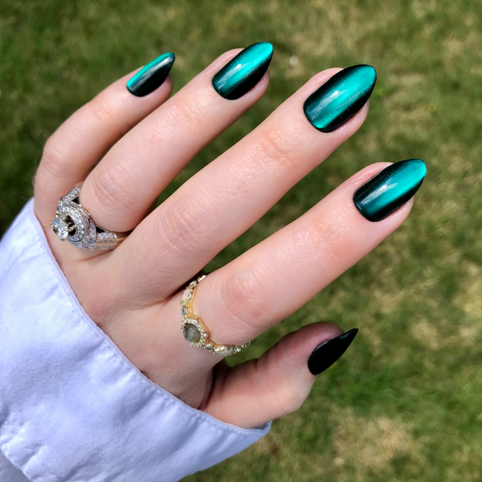 Team Letter - Press-On | Medium | Almond showing metallic emerald green press-on nails styled with rings and white cuff