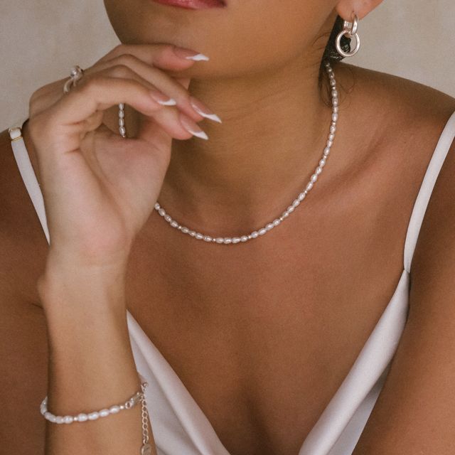 Close-up portrait of a woman adorned with matching silver jewelry featuring sparkling pearls