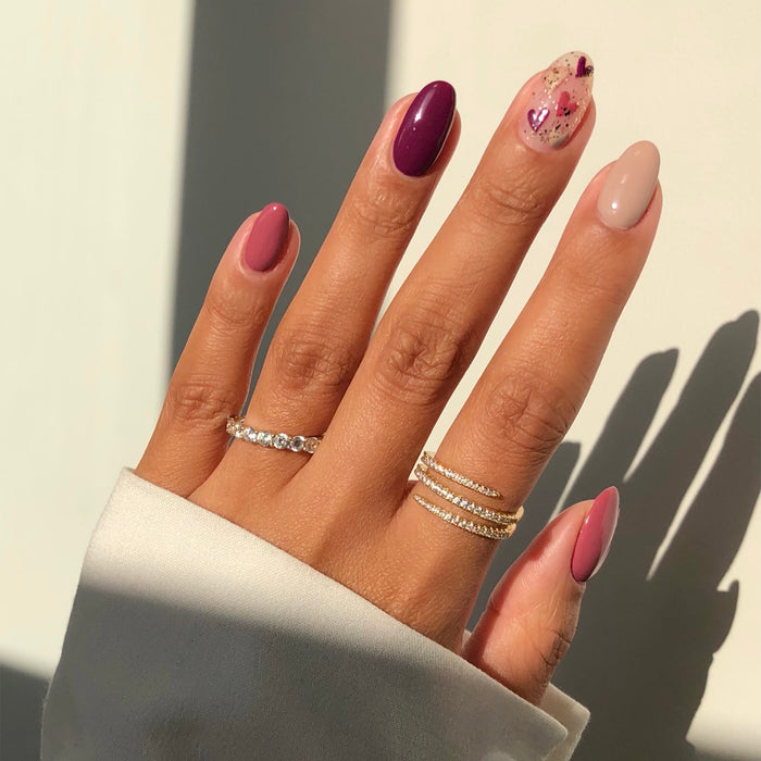 Time for a Bond-fire mauve and plum mix-and-match manicure with rings in sunlight