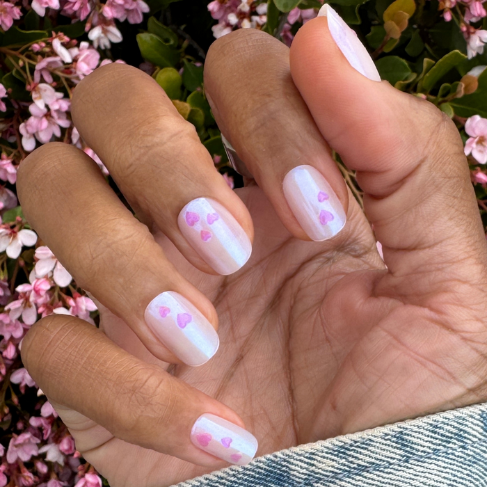 Tiny Puffy Hearts - Press-On | Short | Squoval showing hand with short squoval nails featuring iridescent base and pink puffy heart designs
