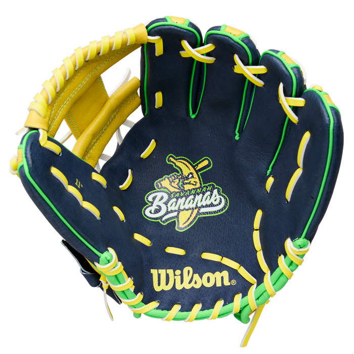 The Wilson A450 Savannah Bananas 11" Youth Baseball Glove (WBW10419211) features navy blue color, yellow and green laces, a cartoon banana with a bat, "Bananas" embroidery on the palm, and a classic H-Web design.